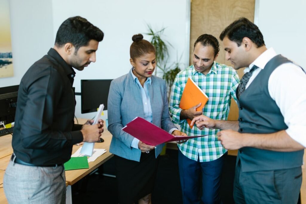 Four colleagues gathered around coloured document folders, reading through the paperwork together.