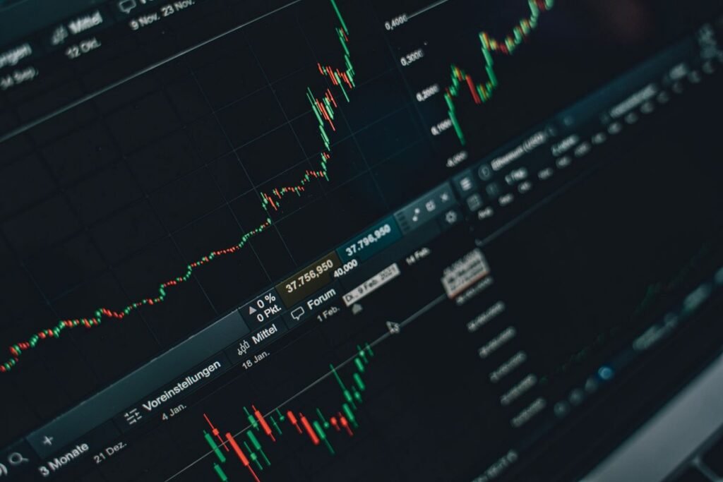 A trading screen showing green and red candlestick charts tracking price movements over several months.